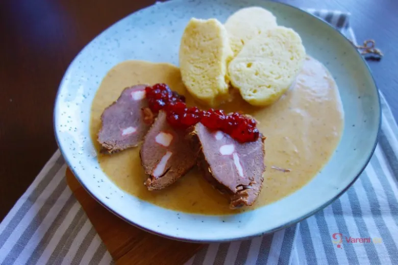Plátované maso v omáčce s červeným ovocem a knedlíky.