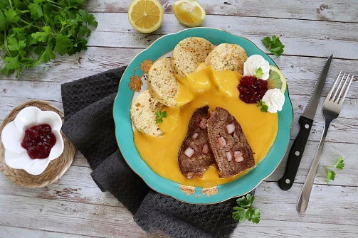 Hotová svíčková s knedlíky a brusinkovou omáčkou na talíři.