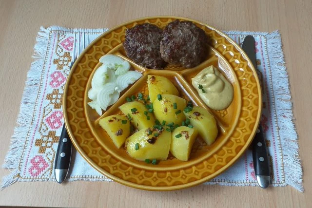 Biftečky z mletého masa s bramborami na talíři.