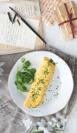 Připravená vaječná omeleta s bylinkami na talíři.