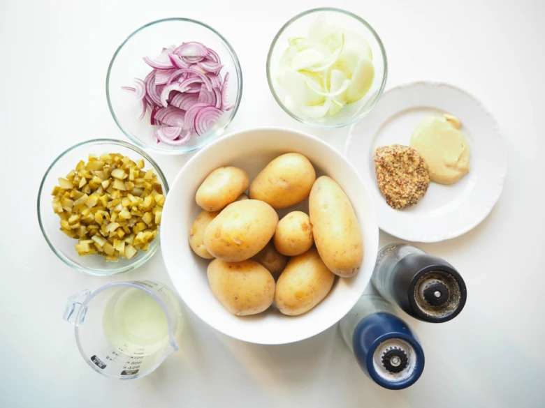 Suroviny na letní bramborový salát: brambory, cibule a okurky.