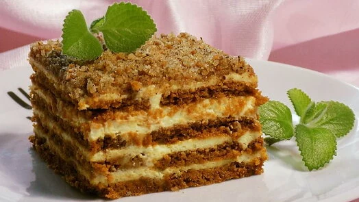 Kus dezertu s vrstvami krému a sušenkou ozdobený mátou.