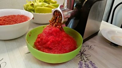Červená paprika se mlýnkem míchá do zelené misky.