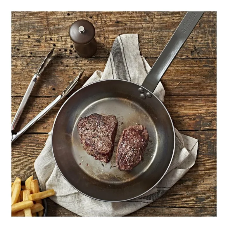 Dva sezónované steak na pánvi se smaží v kuchyni.
