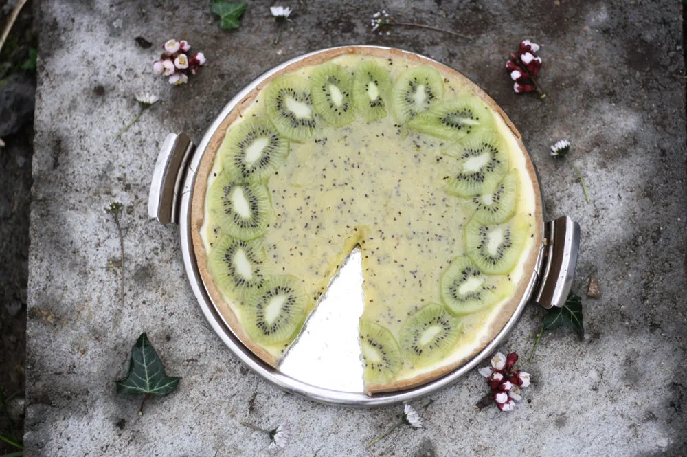 Pečený cheesecake s mascarpone ozdobený kivi, jedna porce vyjmutá.