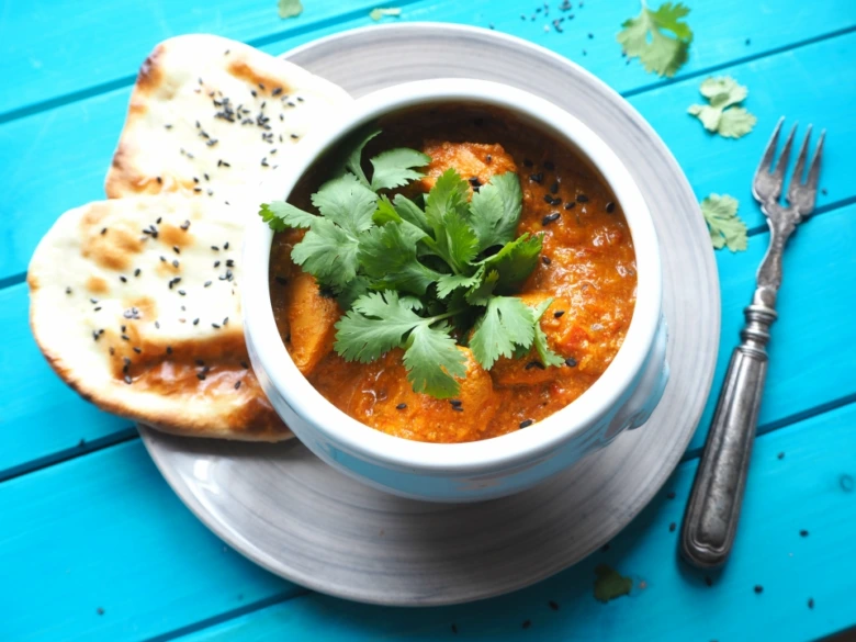 Mísa s kuřecím tikka masalou, koriandrem a chlebem naan.