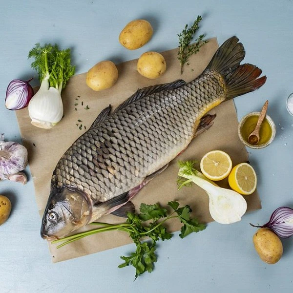 Celá ryba s čerstvými zeleninovými ingrediencemi na papíře.