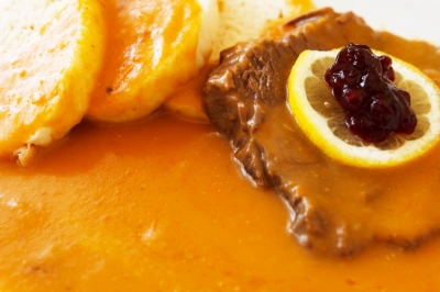 Hotová svíčková s citronem a chlebíčky na talíři.
