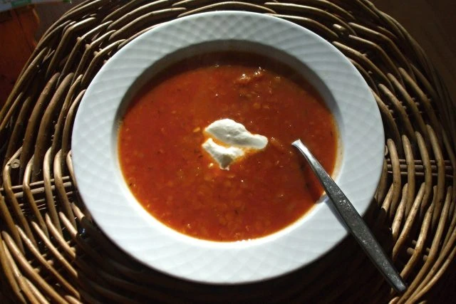 Mísa červené čočkové polévky s kysanou smetanou.