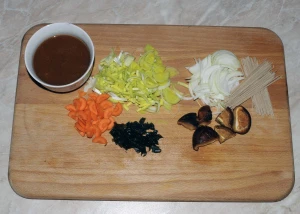 Ingredience pro polévku z misa na dřevěném prkénku.