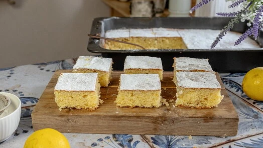 Kusky citronové bábetu posypané cukrem na dřevěném prknu.