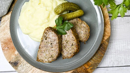 Příprava sekaná s bramborovou kaší a okurkami na talíři.