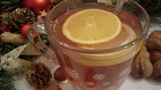 Sklenička s pečeným vínem nebo zimním nápojem ozdobená citronovou kůrou.