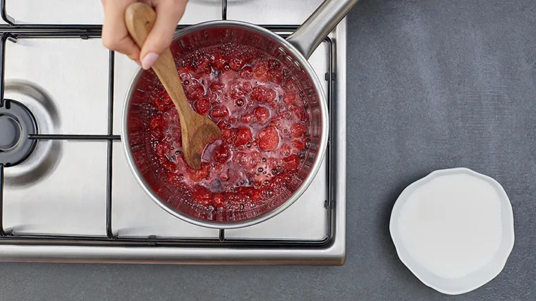 Boiling raspberry coulis in saucepan