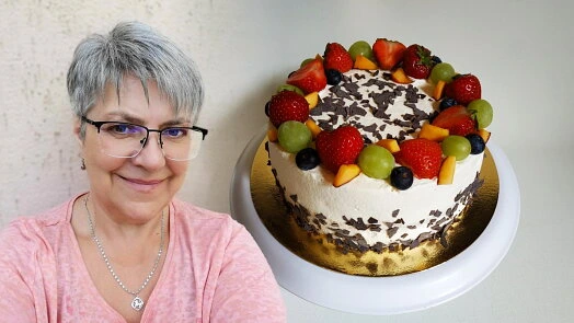 Žena stojí vedle dezertu s ovocem na bílém podkladě.