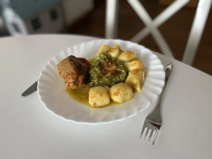 Přesnídané vepřové výpečky se špenátem a knedlíky na talíři.
