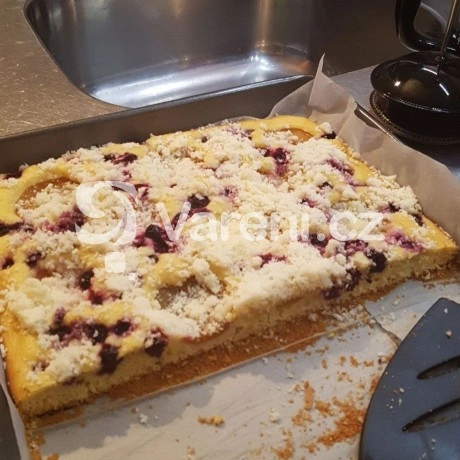 Kousek ovocného koláče s křupavou vrstvou na papíře.