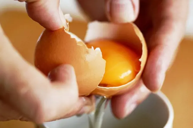 Ruce kladou vejce do misky pro recept volské oko.