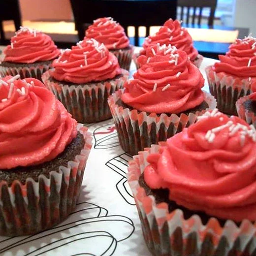 Čokoládové muffiny s červenou glazurou a bílými stříbrkami.