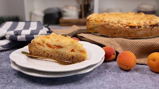 Kousek litého meruňkového tvarohového koláče s celými ovocem.