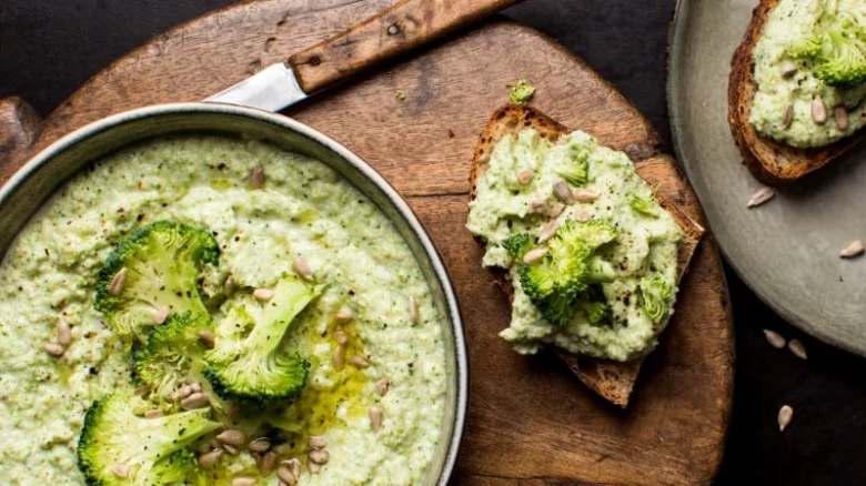 Krušková polévka z brokolice s toastsy na dřevěném podnosu.