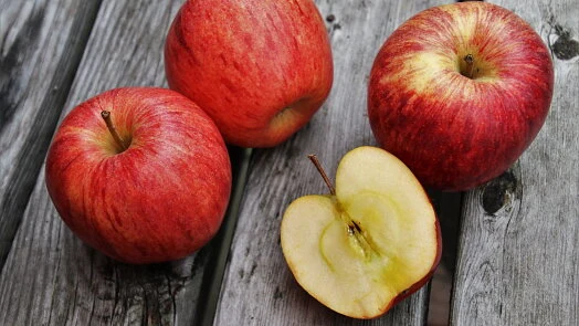 Čtyři červená jablka na dřevěném povrchu.