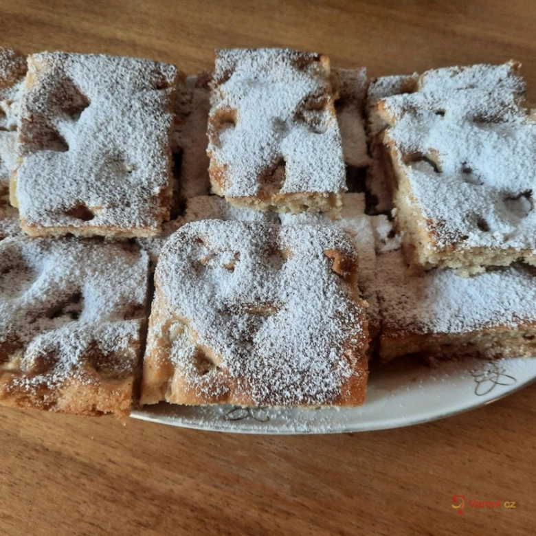 Kusky obráceného jablečného koláče posypané moučkou cukrovou.