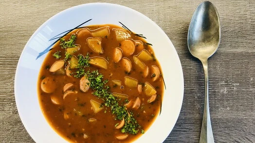 Miska s frankfurtskou polévkou na dřevěném stole.