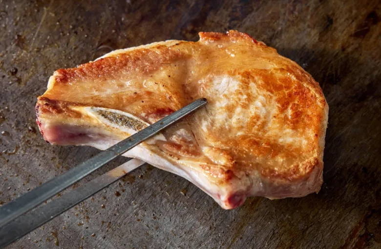 Připravený vepřový medailon na grilu s kouskem kosti.