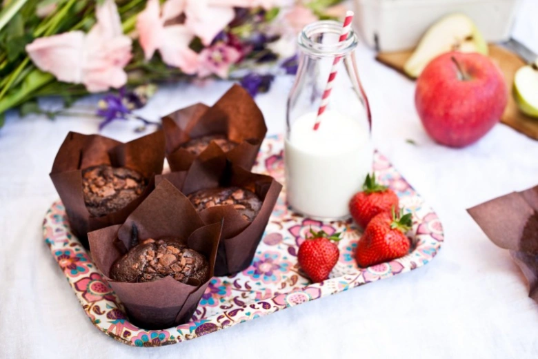 Čokoládové muffiny s mlékem a jahodami na podnose.