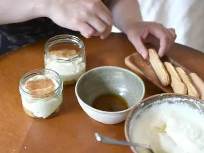 Příprava italského tiramisua s dámskými prsty, kávou a mascarpone.