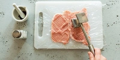 Ruce se kladou na maso pomocí mlátka pro řízky.