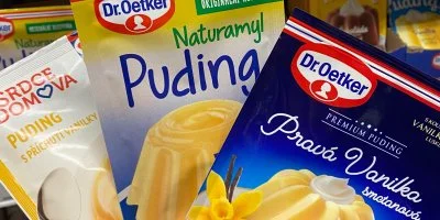 Balíčky pudinku od různých značek na regálu v obchodě.