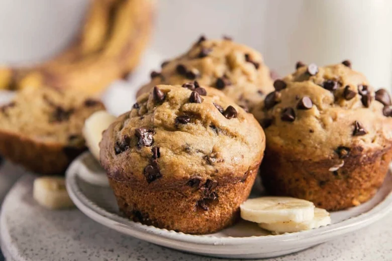 Zlatohnědé banánové muffiny s čokoládovými kousky na talíři.