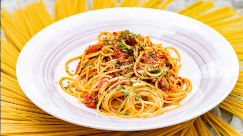 Spaghetti s rajčatovou omáčkou na bílém talíři.