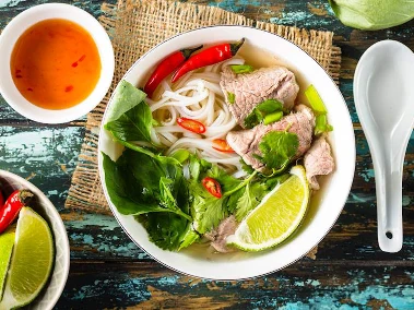 Mísa vietnamské polévky s nudlemi, masem a citronovou šťávou.