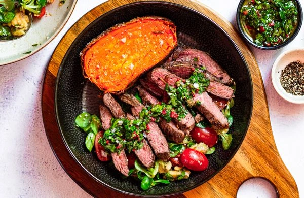Smažený hovězí steak s dušenou bramborou a česnekovou omáčkou.