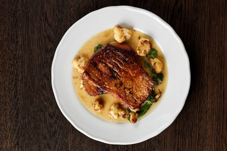 Steak s omáčkou a zeleninou na bílém talíři