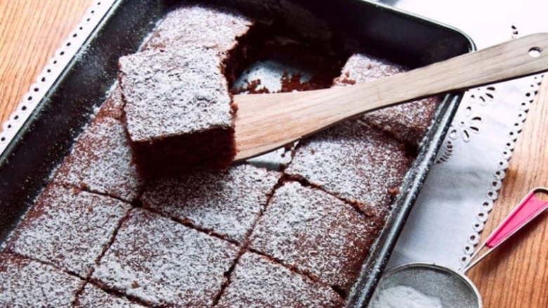 Čokoládové brownie v plechu posypané cukrem pudrem.