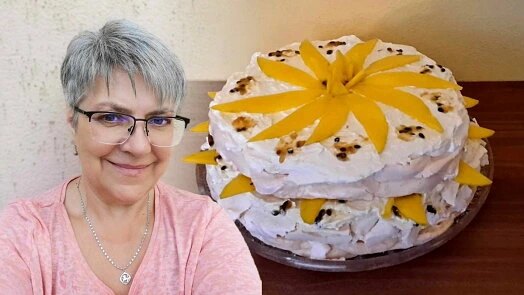 Žena stojí vedle velkého dortu Pavlovy s mangem.
