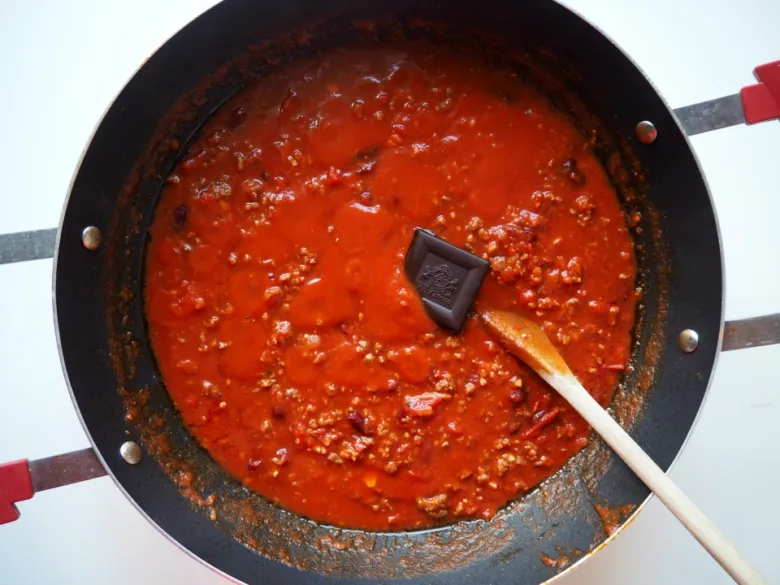 Připravená chilli s masem v pánvi se špetkou čokolády.