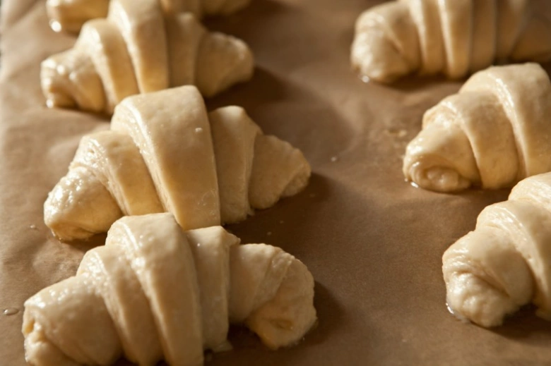 Nepečené croissants na pečicím papíru před pečením.