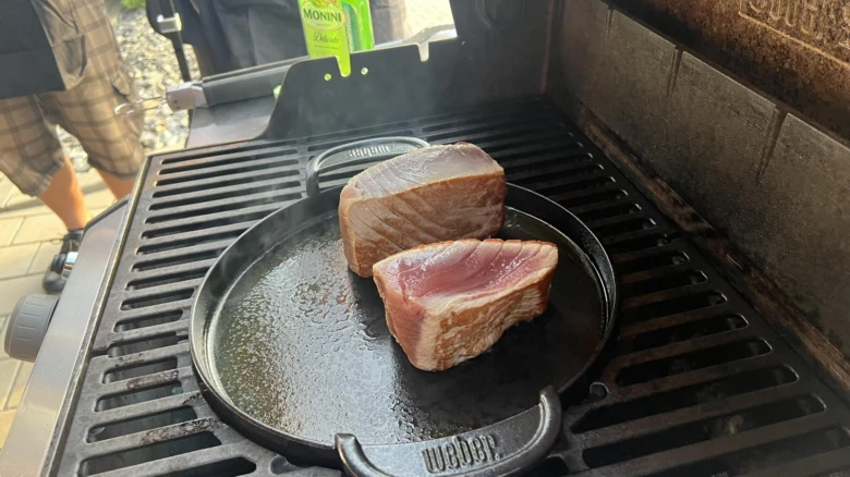 Dva pečené tuňákové steak na pánvi nad grilem.