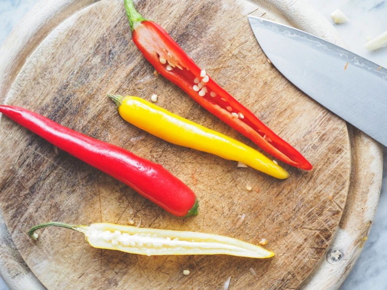 Červené a žluté chilli papričky nakrájené na dřevěném prkénku.