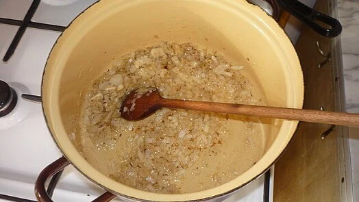 Cibule se smaží v hrnci na plynové varné desce.