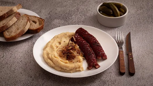 Pohanka s bramborami, klobásou a chlebem na talíři.