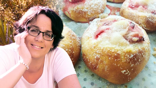 Žena se usmívá vedle svatebních koláčů posypaných cukrem.