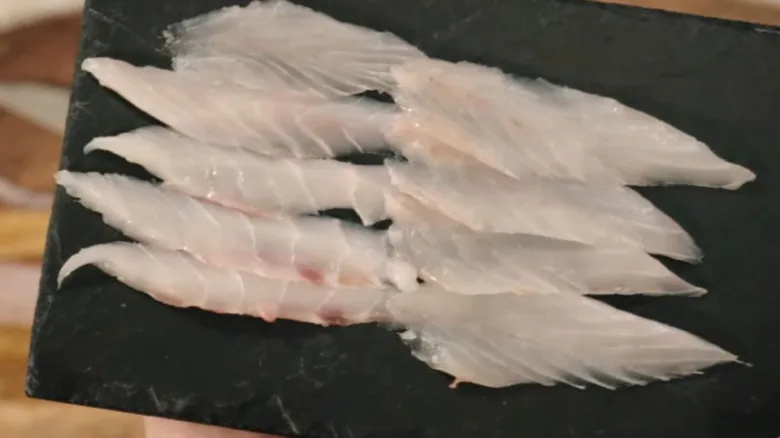 Surové rybí filéty na desce pro domácí přípravu sushi.