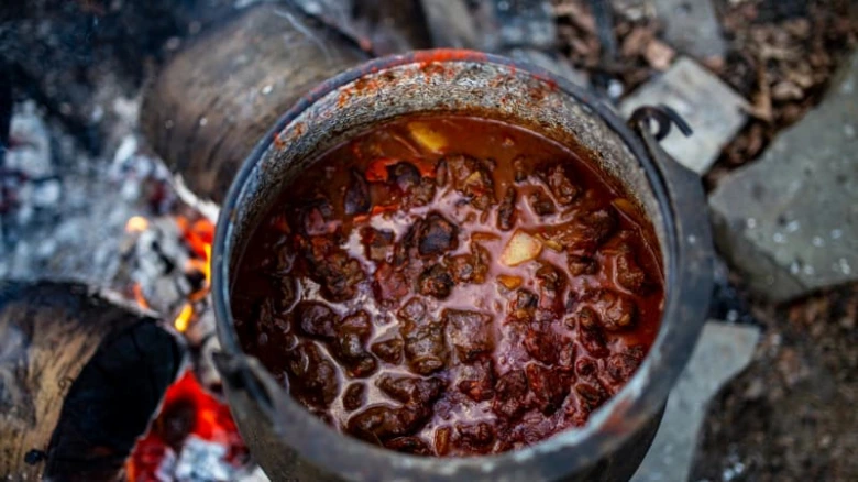 Hot guláš v hrnci nad ohněm připravený venku.