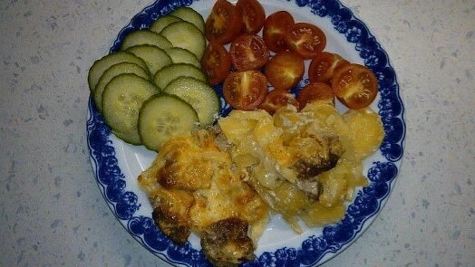 Zapečené vepřové kotlety s okurkou a rajčaty na talíři.
